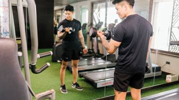 Ein Fitnessraum mit Laufbändern, Gewichten und einem Spiegel.