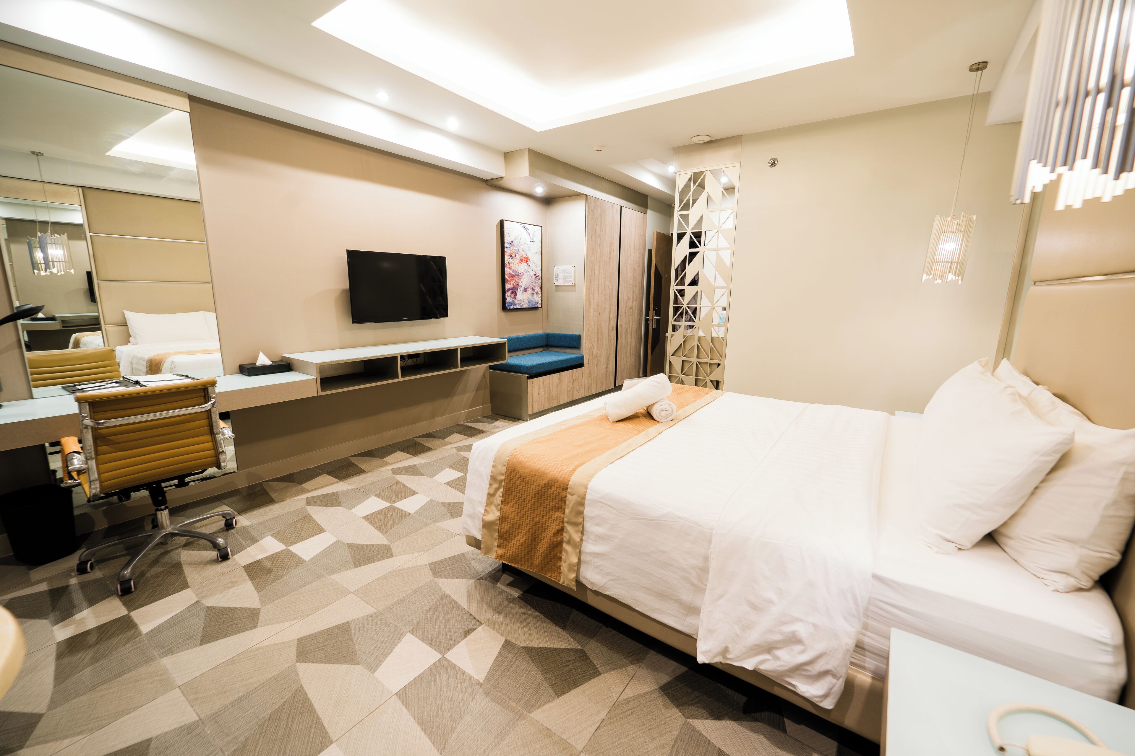 Une chambre d’hôtel moderne équipée d’un grand lit, d’un bureau, d’une chaise, d’une télévision et d’une salle de bain.