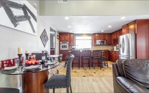 A spacious kitchen with wooden cabinets, a stainless steel refrigerator, and a central island with seating. - Heart of LA Large single level pool BBQ home (Chino)