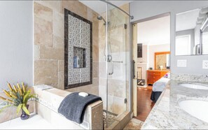 A modern bathroom with a glass shower enclosure, a marble sink, and a decorative wall panel.