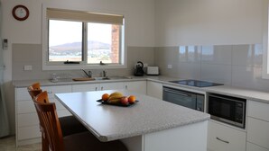 Une cuisine moderne avec des meubles blancs, une grande fenêtre et une vue sur la ville.