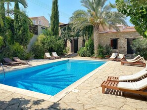 Relax by the serene pool surrounded by lush greenery and comfortable lounge chairs.