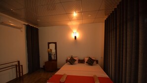 Une chambre d’hôtel avec un grand lit, une table de chevet, un miroir et un luminaire fixé au mur.