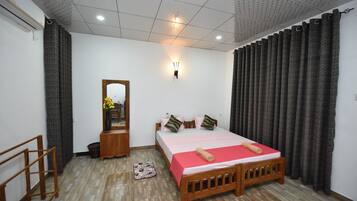 A bedroom with a wooden bed, a bedside table, a mirror, and a small stool.