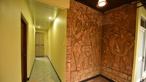 Un couloir doté d’un sol carrelé, d’une porte en bois et d’un mur orné d’une sculpture d’éléphant aux détails complexes.