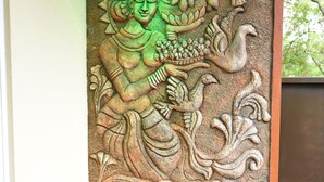 Un mur sculpté représentant une figure tenant une fleur de lotus.