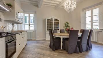 A spacious kitchen with white cabinetry, a wooden dining table, and a chandelier.