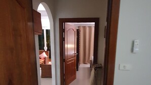A hallway with a wooden door frame, a white wall, and a light switch.