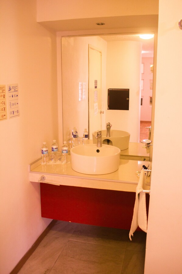 A bathroom with a large mirror, a sink, and a red cabinet.
