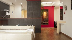 A modern bathroom with a large bathtub, a mirror, and a red accent wall. - Motel LA Autoparador (Morelia)