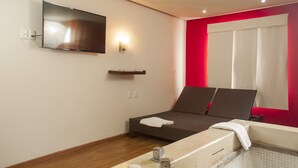A modern hotel room with a bed, a TV mounted on the wall, a small shelf, and a window with curtains. - Motel LA Autoparador (Morelia)