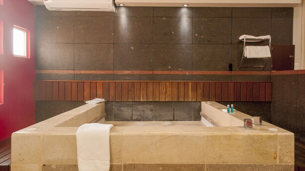 A modern bathroom with a freestanding bathtub, a wooden panel accent, and a mirror above the tub. - Motel LA Autoparador (Morelia)