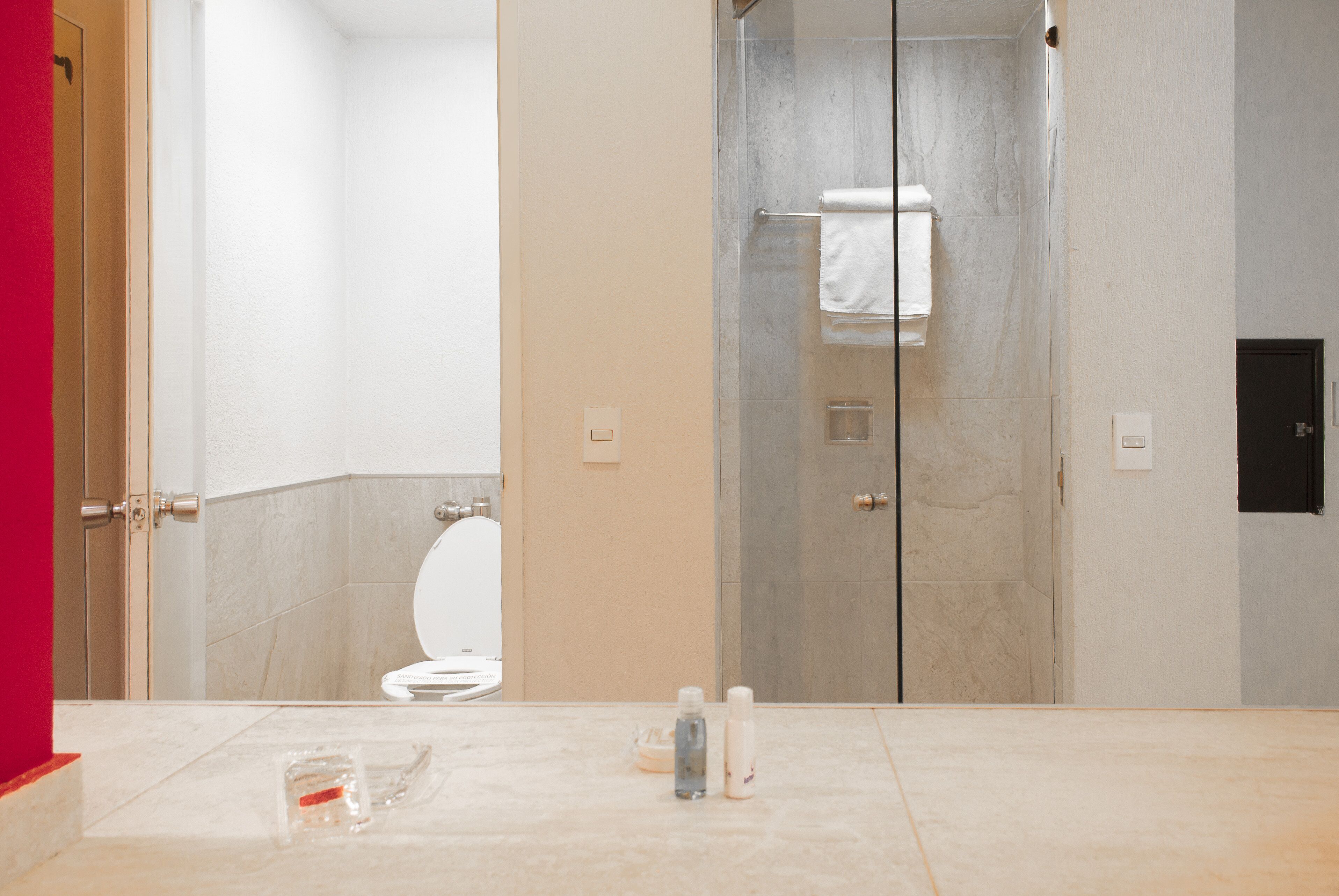 Un baño con inodoro, cabina de ducha de vidrio y suelo de losa de mármol.