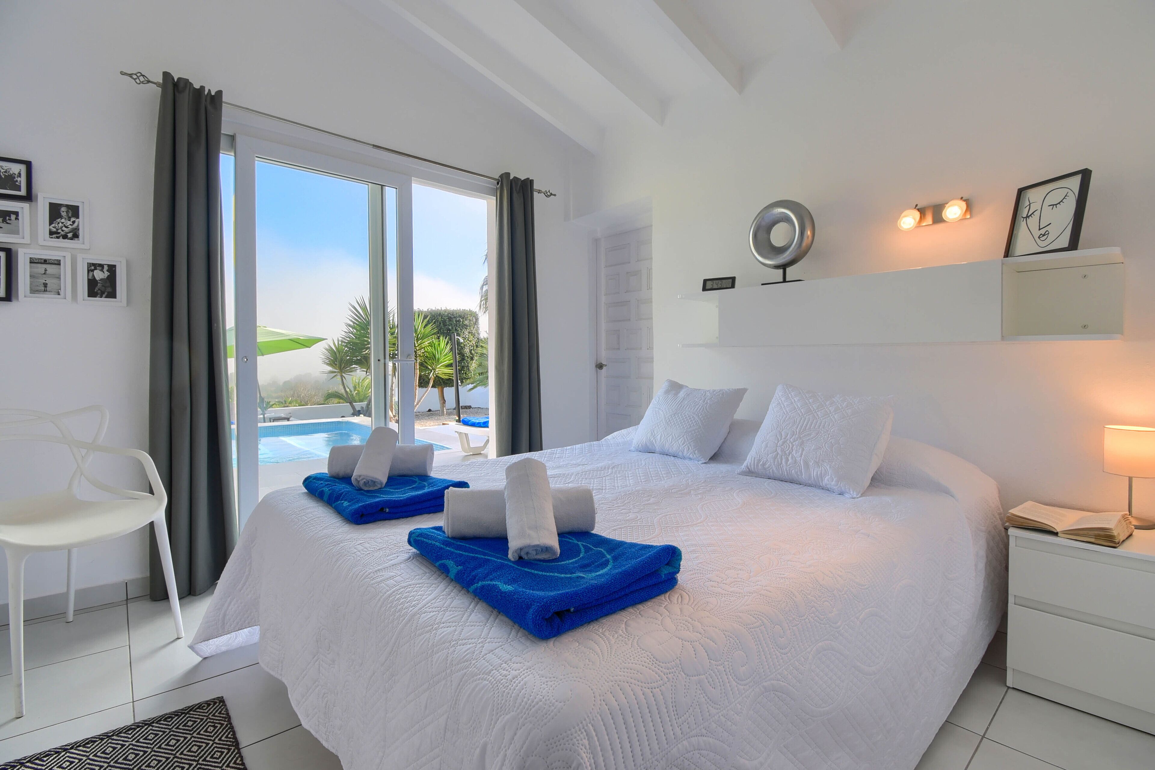 Une chambre d’hôtel avec un grand lit, une chaise, une table de chevet avec une lampe et une vue sur une piscine.