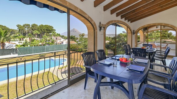A balcony with a pool, dining area with chairs and tables, and a view of trees and a mountain. - Jasmin 6 pax - Javea, Costa Blanca (Javea)