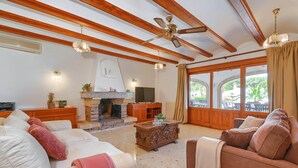 A spacious living room with a fireplace, wooden beams, and large windows. - Jasmin 6 pax - Javea, Costa Blanca (Javea)