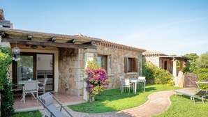 Una casa de piedra con patio, mobiliario exterior y jardín.