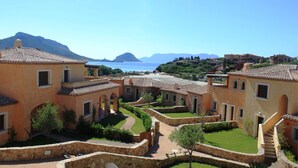 Un pueblo costero con arquitectura mediterránea tradicional, con tejados de teja, muros de piedra y un patio central con senderos.