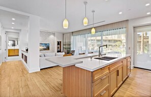 Enjoy a spacious kitchen and living area with a central island, comfortable sofa, and large window offering a view of the outdoors.