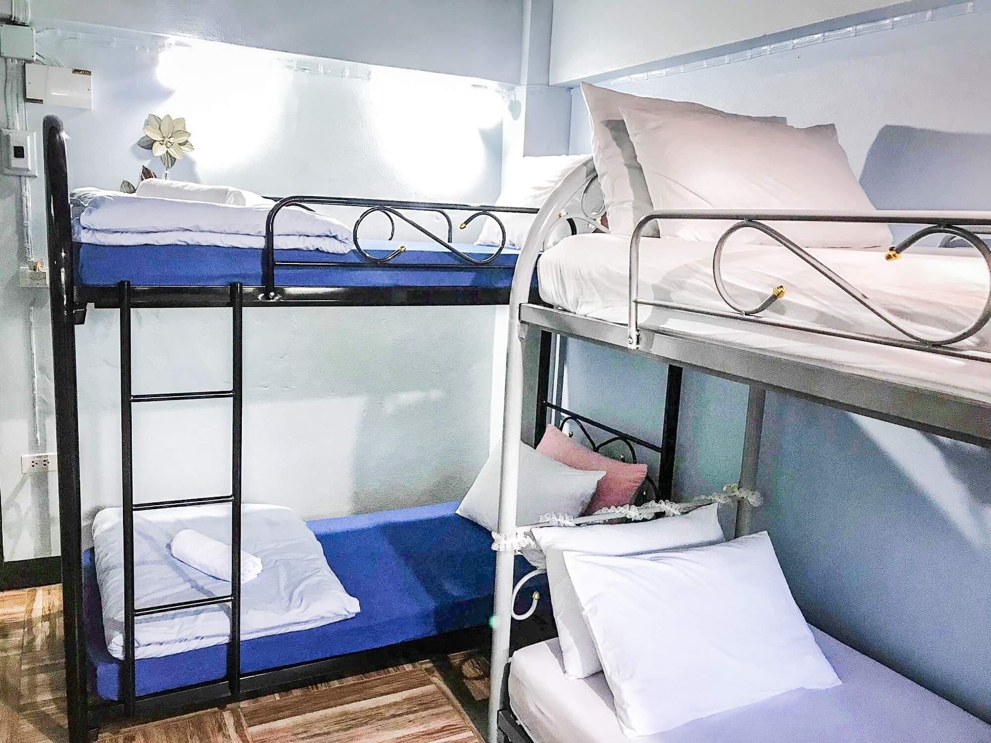 A bunk bed room with a window, a flower, and a wooden floor.