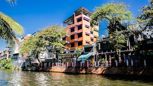 A riverside building with multiple balconies and a water body in front. - Bangkok Canale Home (Bangkok)