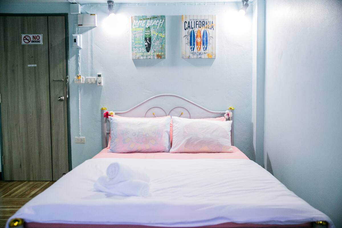 A bedroom with a bed, a 'No Smoking' sign, and two posters on the wall.