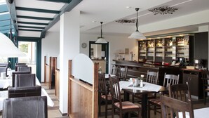 Un restaurante con cabinas de madera, zona de bar y vistas al exterior.