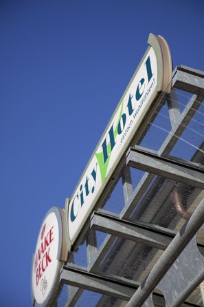 A hotel sign with the name "City Hotel" and a smaller sign below it that says "Take Beck."