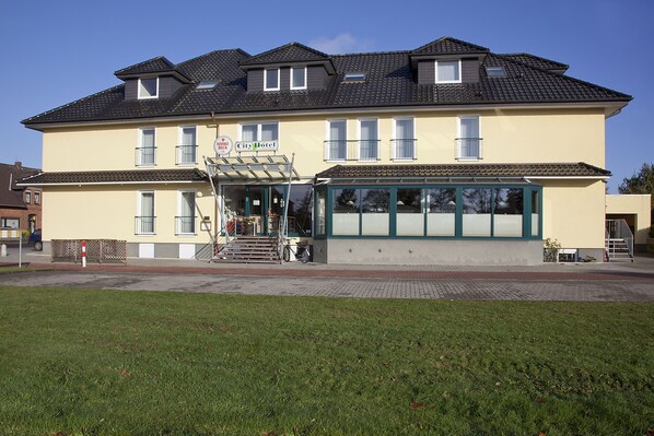 A two-story hotel with a flat roof, large windows, and a sign indicating it is a City Hotel.