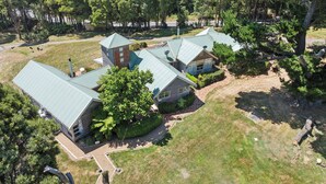A residential property with multiple houses, each featuring a green metal roof, surrounded by lush greenery and trees.
