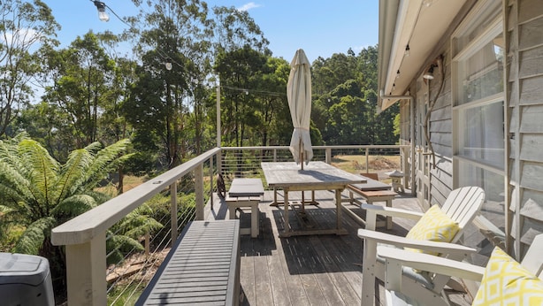 A wooden deck with outdoor furniture, including a table and chairs, and a covered area with an umbrella.