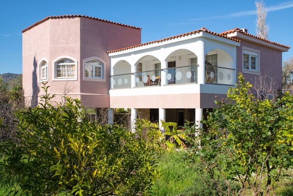 A two-story house with a balcony, arched windows, and a red-tiled roof.