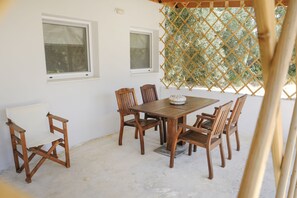 A wooden dining table with six chairs, two windows, and a lattice screen.