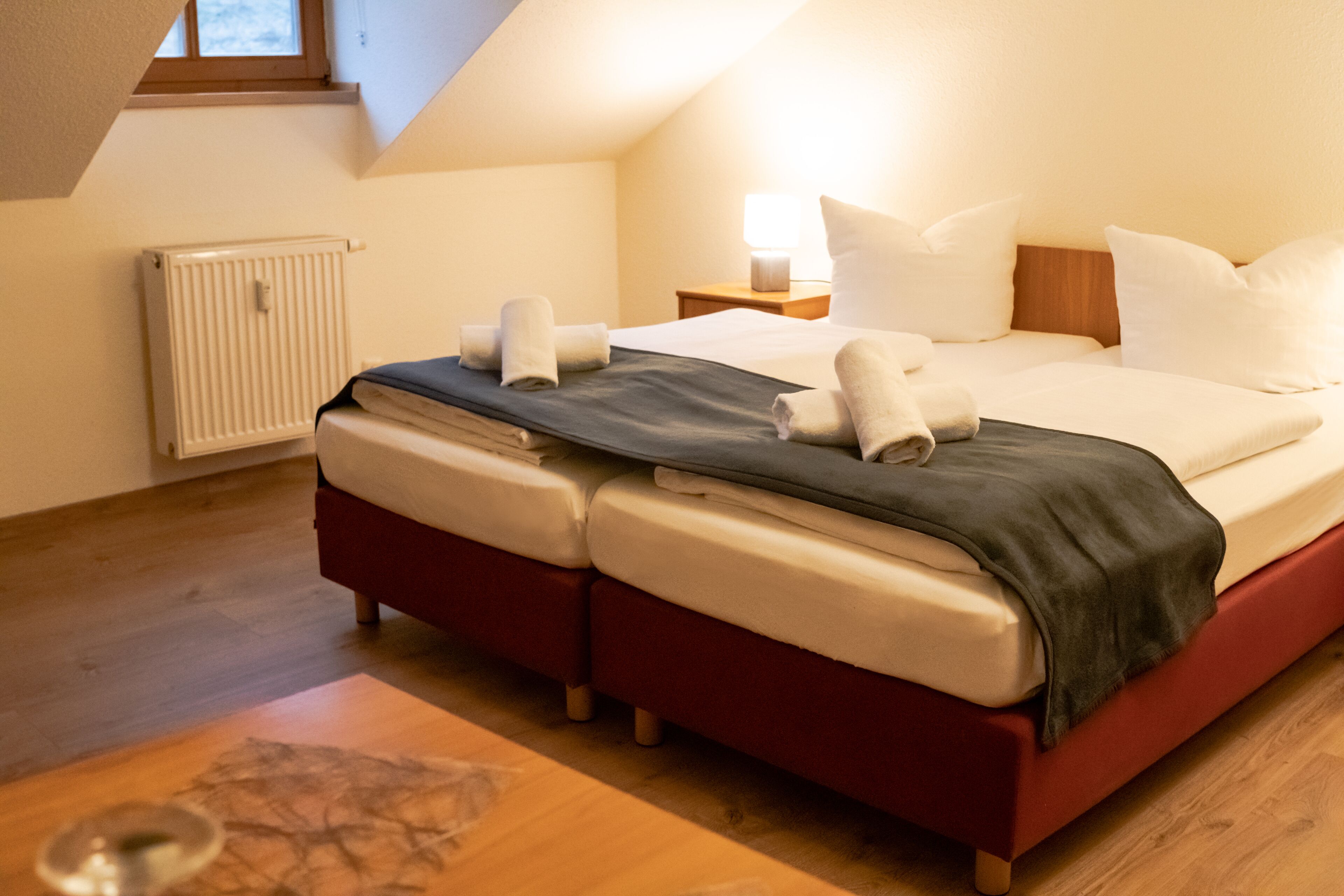 Quarto com cama, almofadas, mesa de cabeceira e janela.