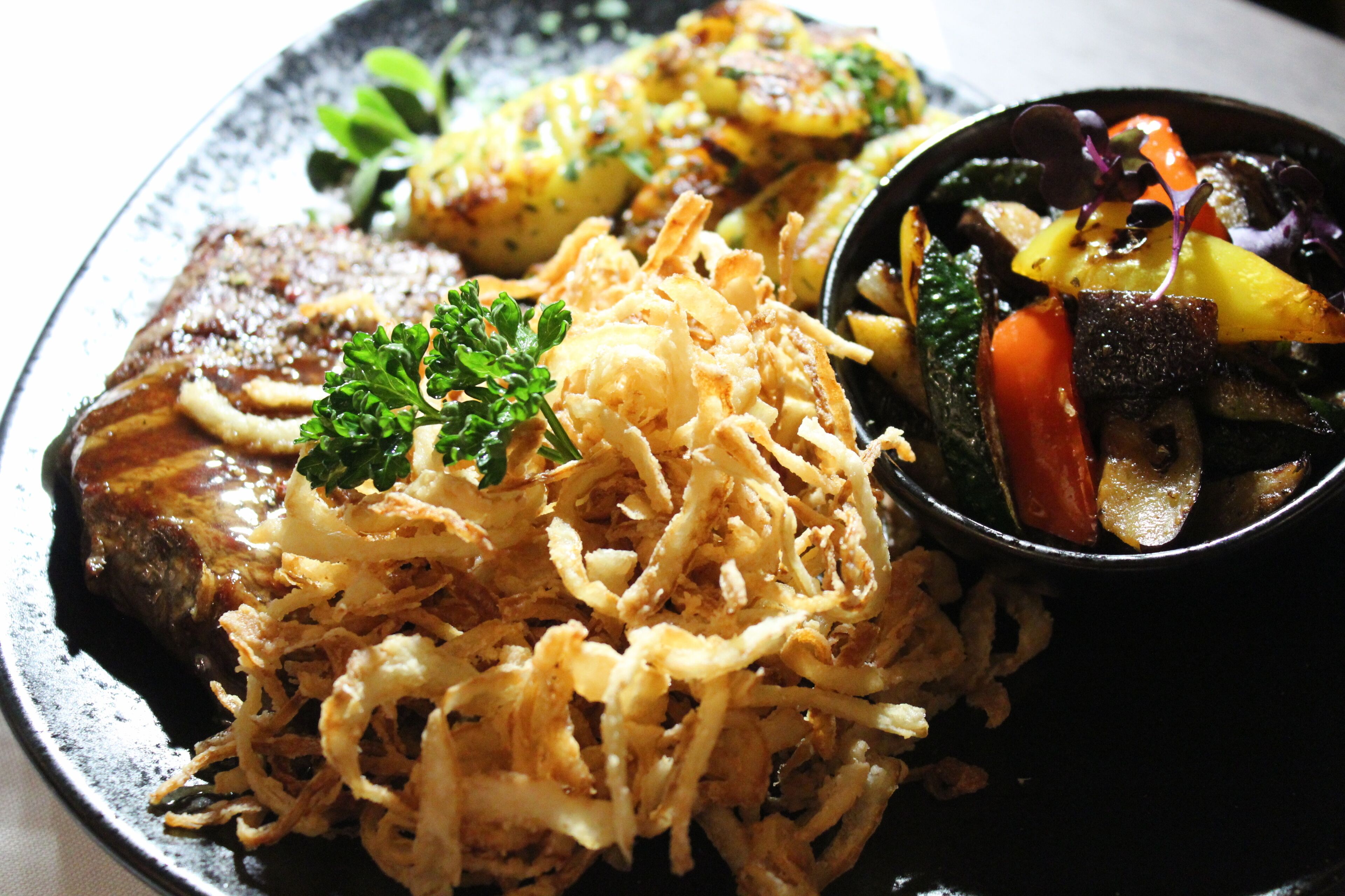 A plate with a variety of food items including a piece of meat, vegetables, and a side of fries.