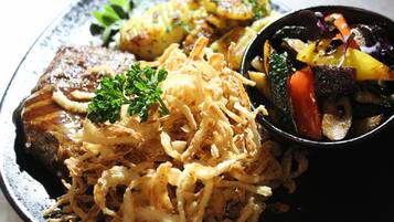 A plate with a variety of food items including a piece of meat, vegetables, and a side of fries.