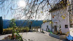 Un hotel con fachada blanca, un patio empedrado y vistas a las montañas.