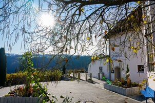 Un hotel con fachada blanca, un patio empedrado y vistas a las montañas.
