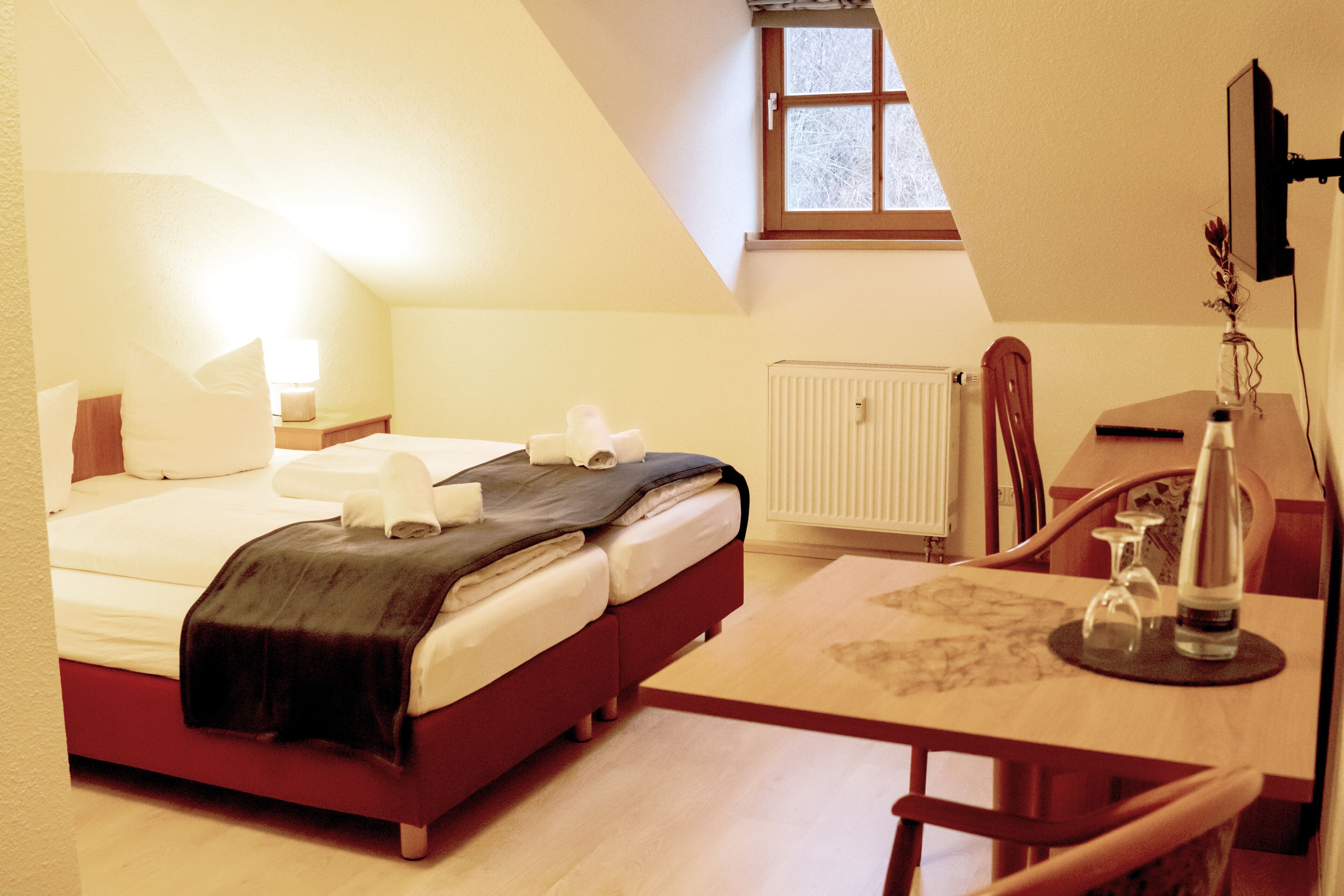 Une chambre à coucher avec un lit, une table de chevet, une lampe et une petite fenêtre.