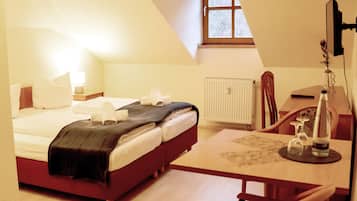 Un dormitorio con cama, mesita de noche, lámpara y una ventana pequeña.