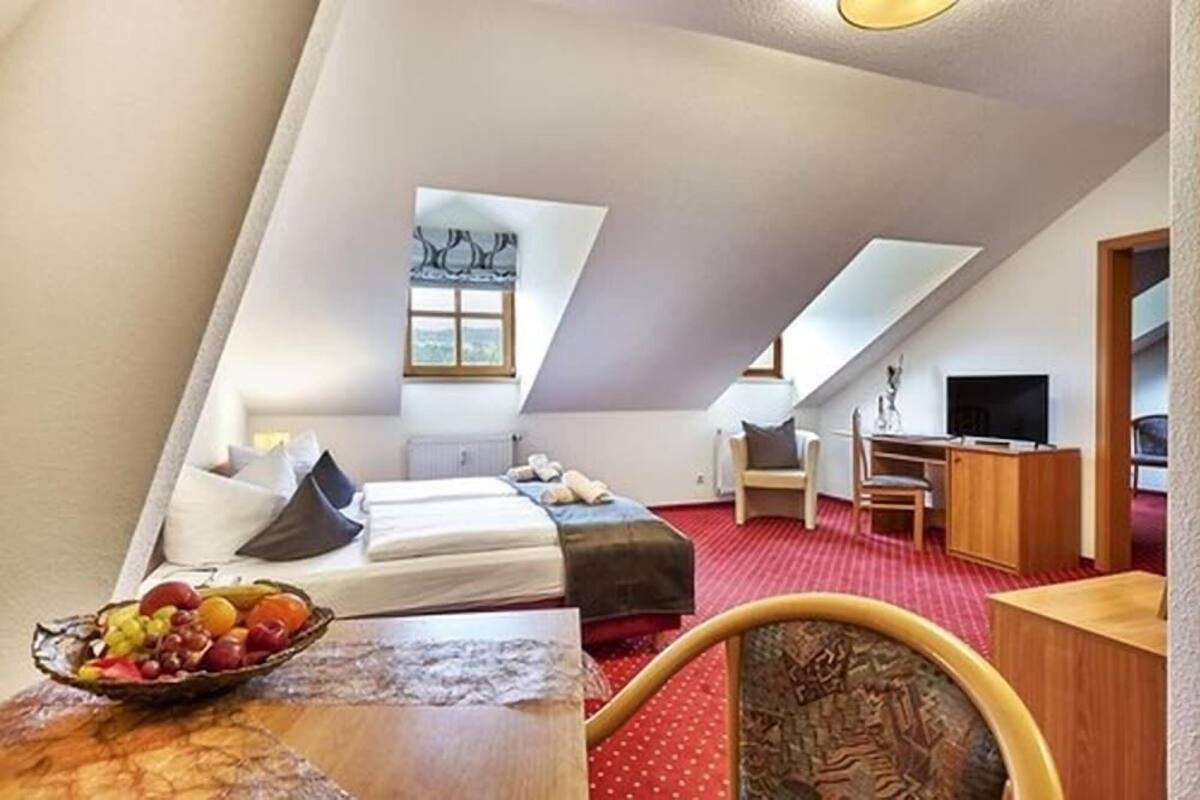 A bedroom with a bed, a desk, a chair, and a television.