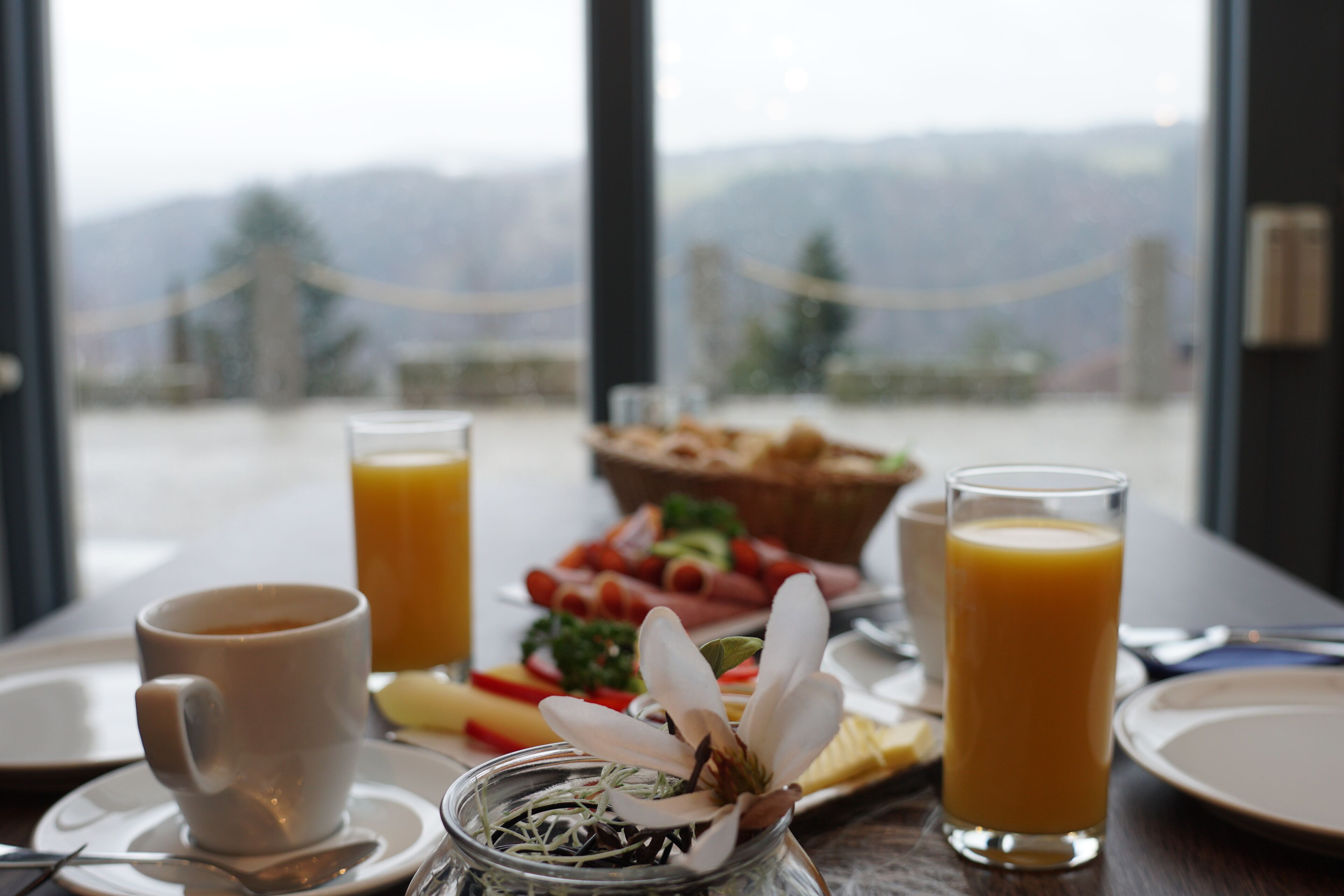 A breakfast setting with a cup, glass of orange juice, and a plate of food.
