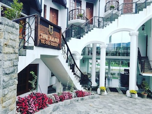 A hotel with a stone facade, a signboard, a staircase, and a balcony with potted plants. - The Ramp Hotel (Nuwara Eliya)