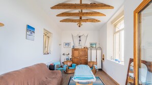 Um quarto aconchegante com um sofá marrom, teto de madeira, tapete azul e um aparador de madeira.