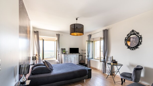 Quarto moderno com cama, mesas de cabeceira, escrivaninha, cadeira e televisão.