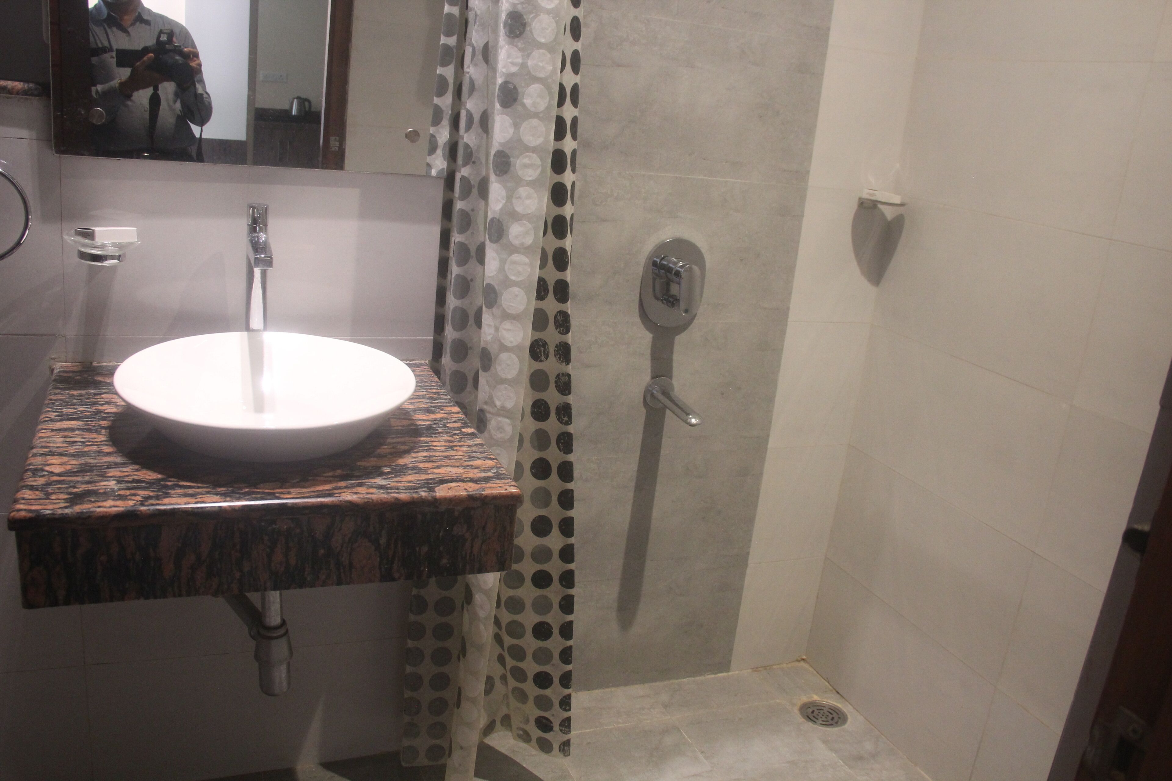 A bathroom with a round sink, a shower with a circular drain, and a mirror above the sink.