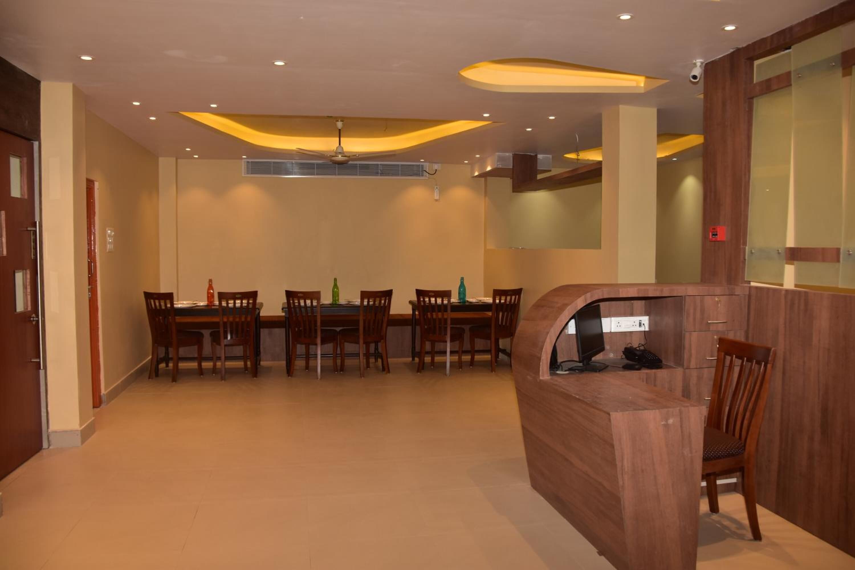 A modern dining area with a wooden table and chairs, a built-in computer station, and recessed ceiling lighting.