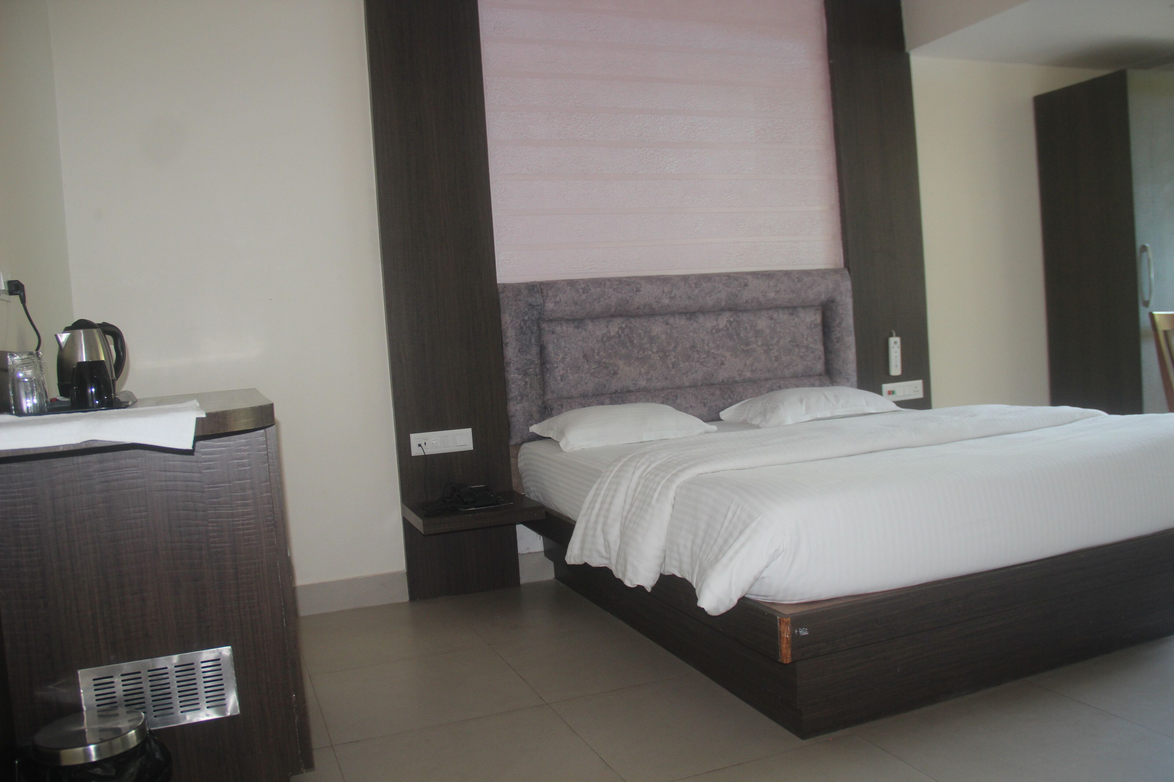 Una habitación de hotel moderna con una cama grande, una mesita de noche y un calentador fijado a la pared.