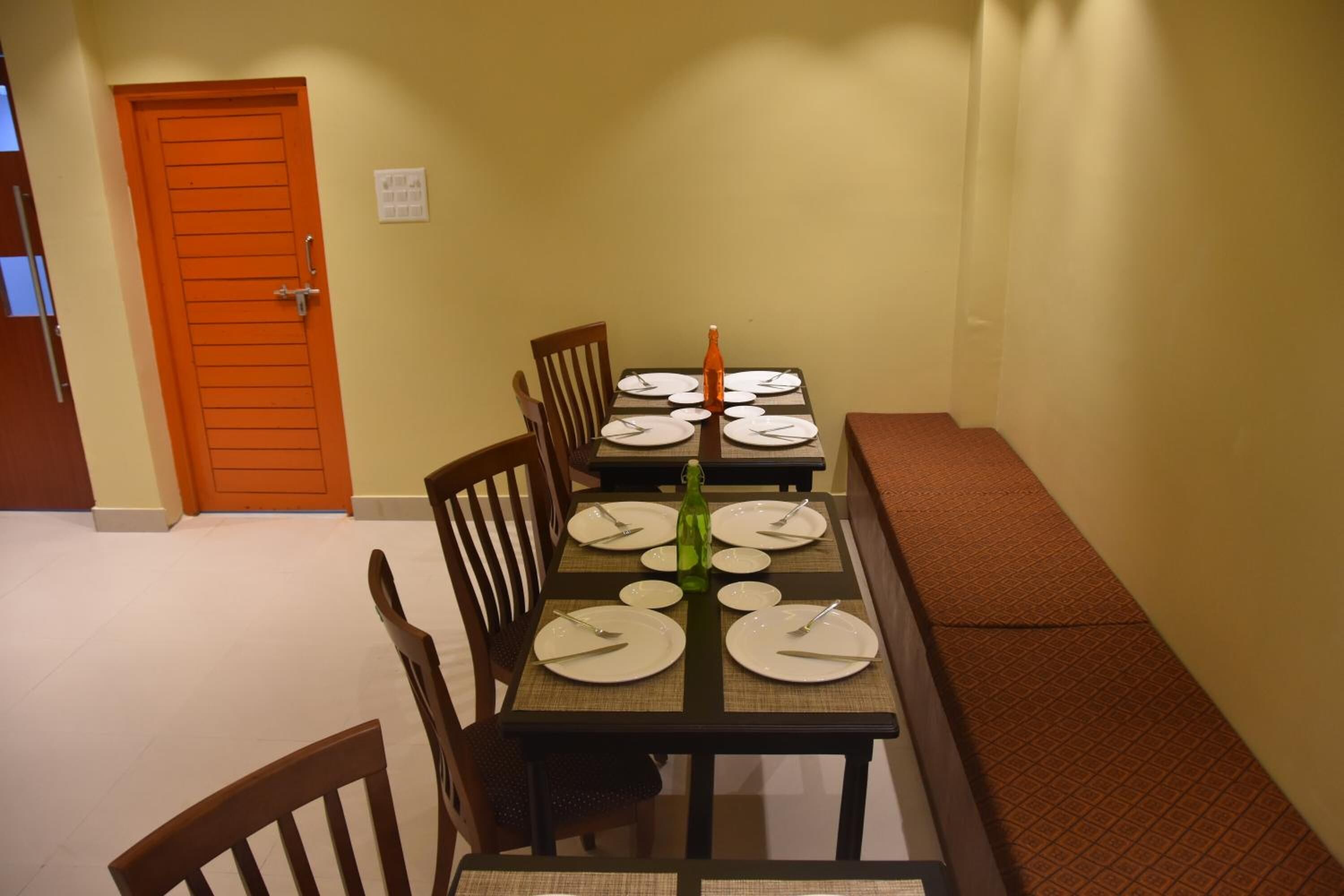 A dining area with a table set for four, chairs, a bench, and a door.