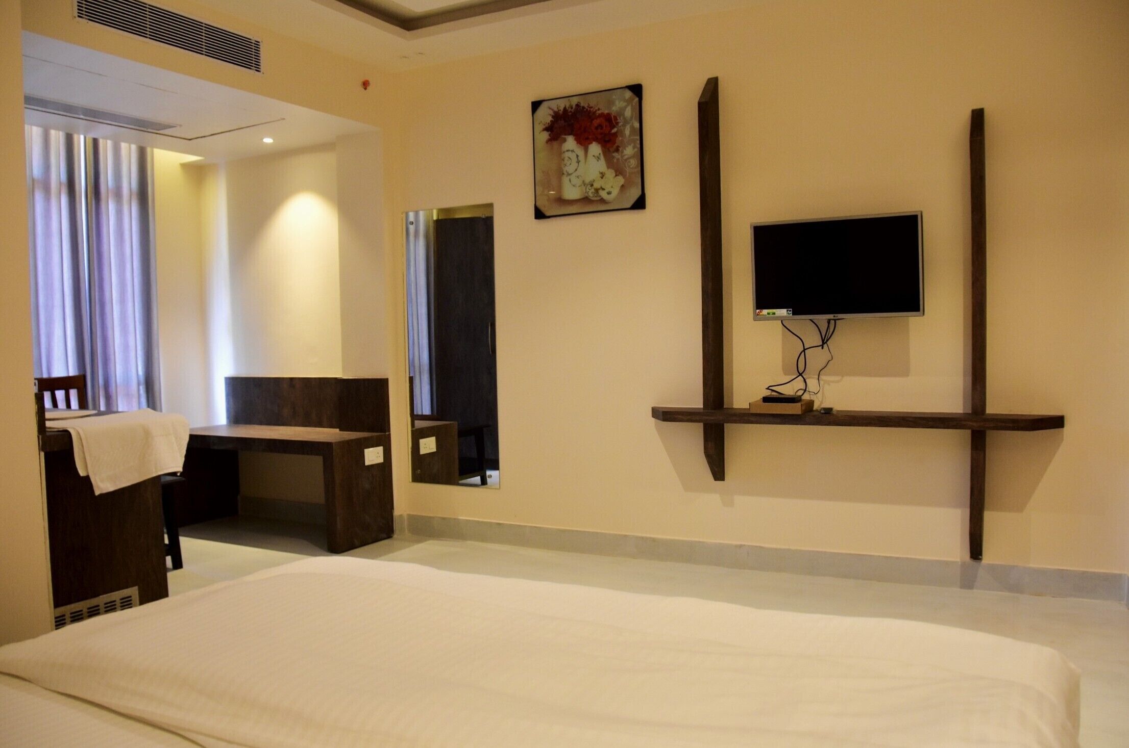 Une chambre d’hôtel équipée d’un lit, d’un bureau, d’une chaise, d’un téléviseur fixé au mur et d’un miroir.